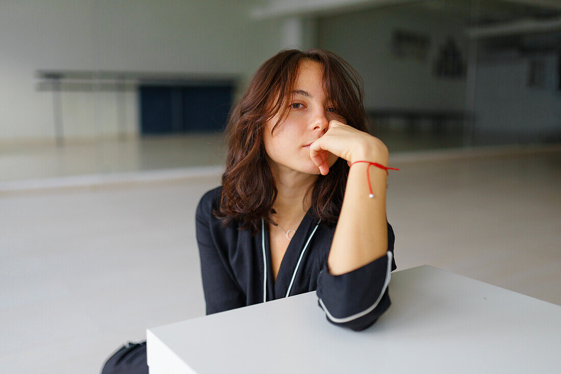 Portrait einer jungen Frau, die im Tanzstudio sitzt und in die Kamera schaut