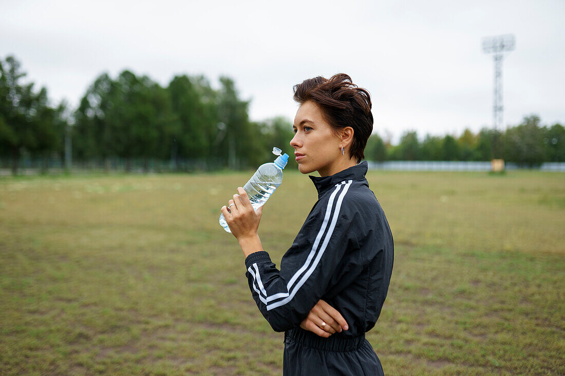 Junge Frau trinkt Wasser nach dem Sporttraining