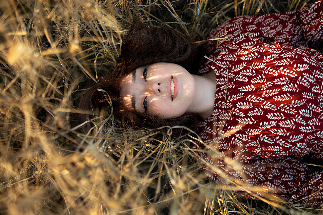 Directly above view of woman lying on cereal plants in field\n