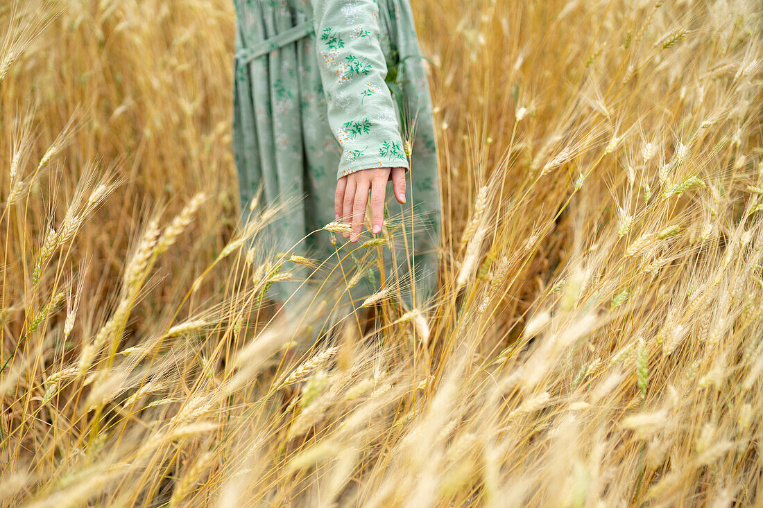 Young woman wearing dress standing in field of wheat \n