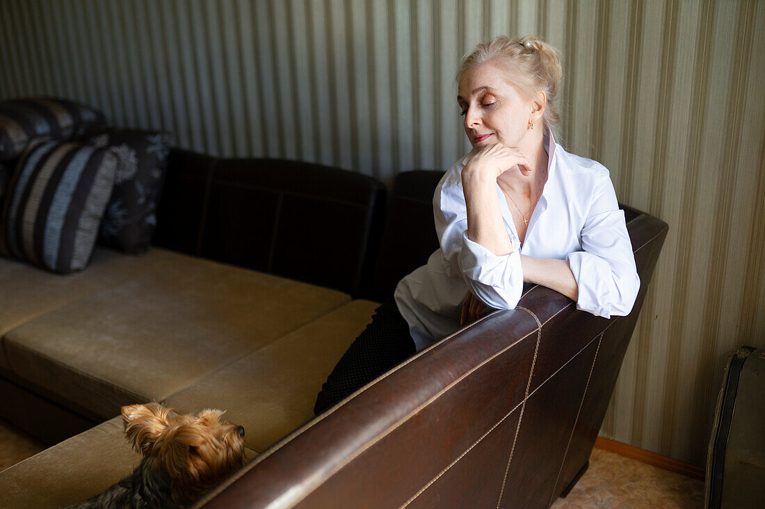 Frau sitzt auf dem Sofa und schaut auf Yorkshire Terrier