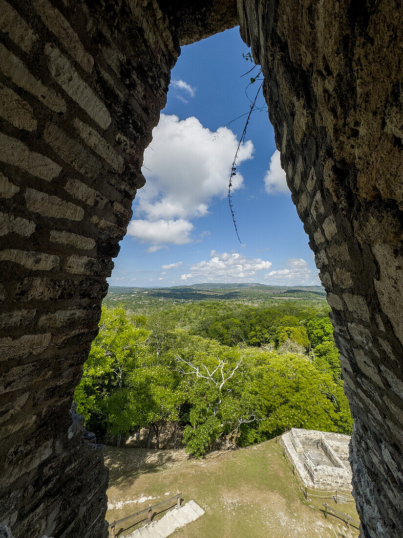 Blick durch einen Kragsteinbogen in El Castillo im archäologischen Reservat Xunantunich in Belize. Guatemala liegt in der Ferne.