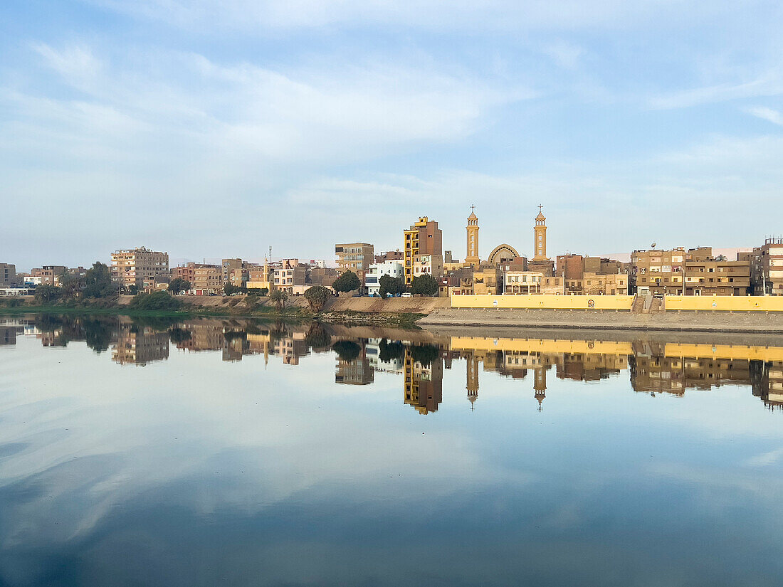 Blick auf Gebäude, die sich im Wasser des Nils spiegeln, Dendera, Ägypten, Nordafrika, Afrika