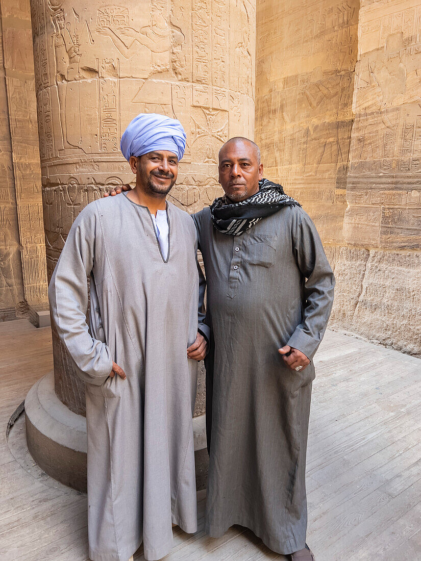 Two Egyptian men standing inside the Philae temple complex, The Temple of Isis, currently on the island of Agilkia, Egypt, North Africa, Africa\n