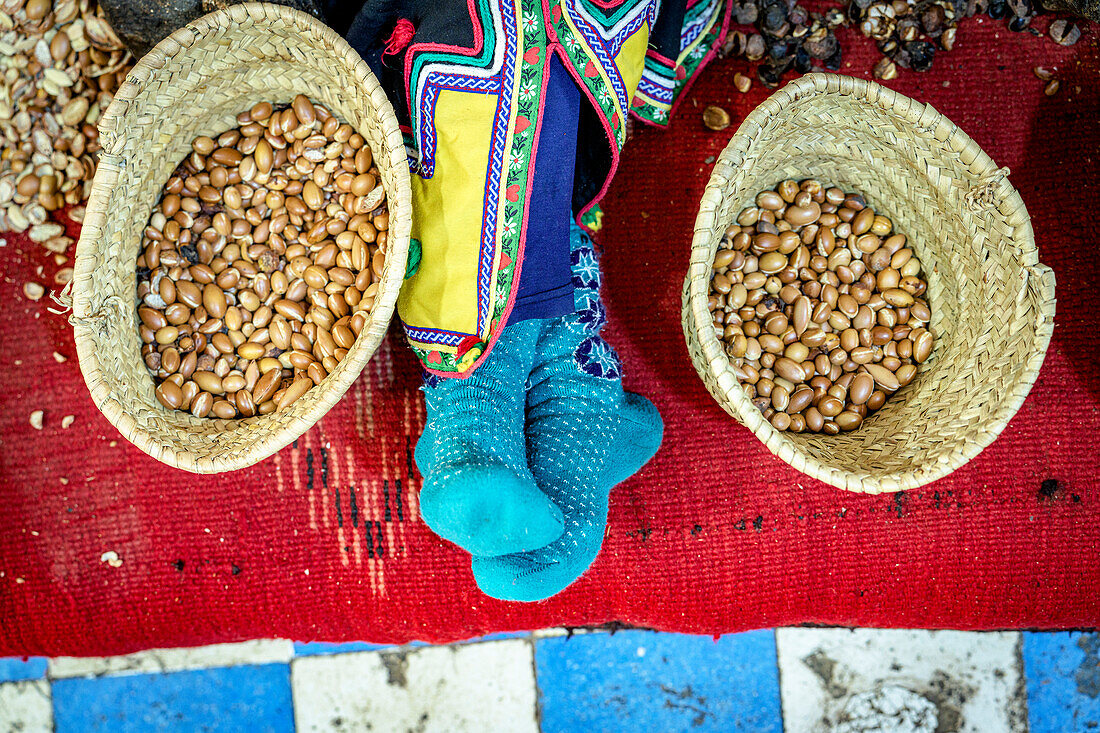 High angle view of worker resting beside straw baskets full of seeds for making argan oil, Morocco, North Africa, Africa\n