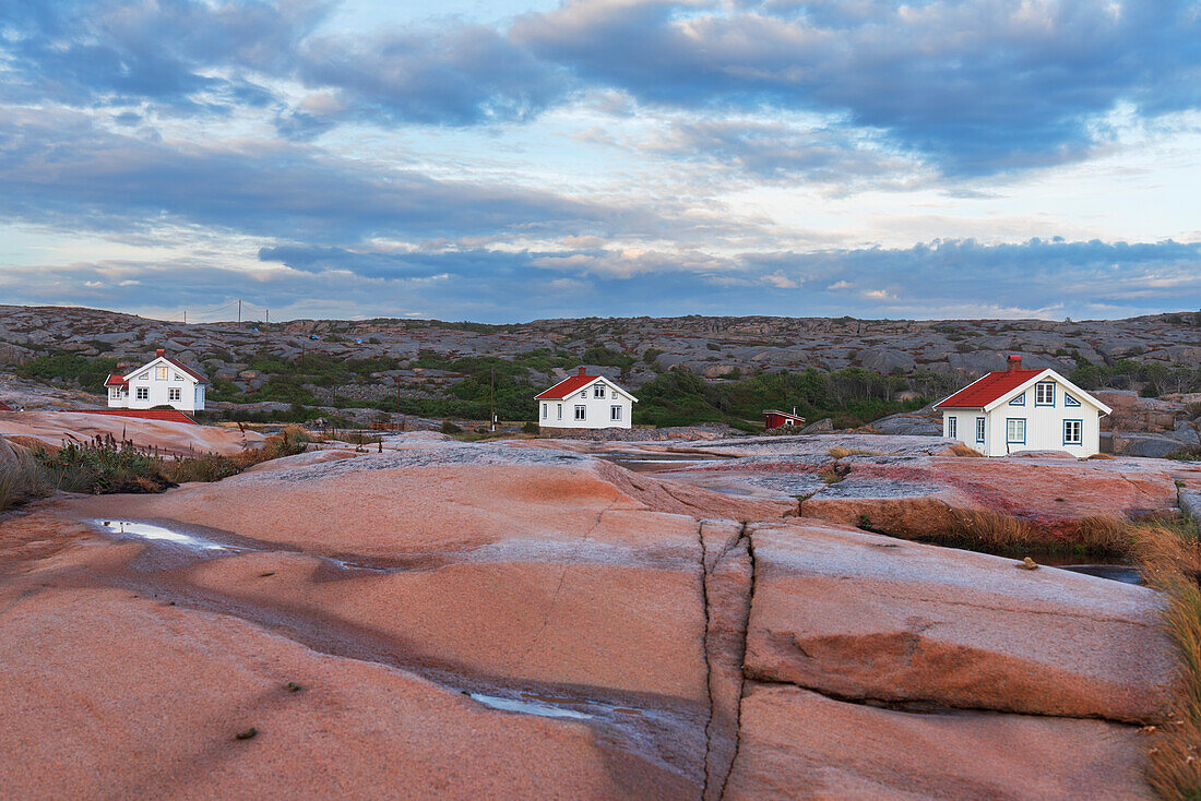Drei isolierte Häuser auf roter Granitinsel in der Abenddämmerung, Bohuslan, Vastra Gotaland, Westschweden, Schweden, Skandinavien, Europa