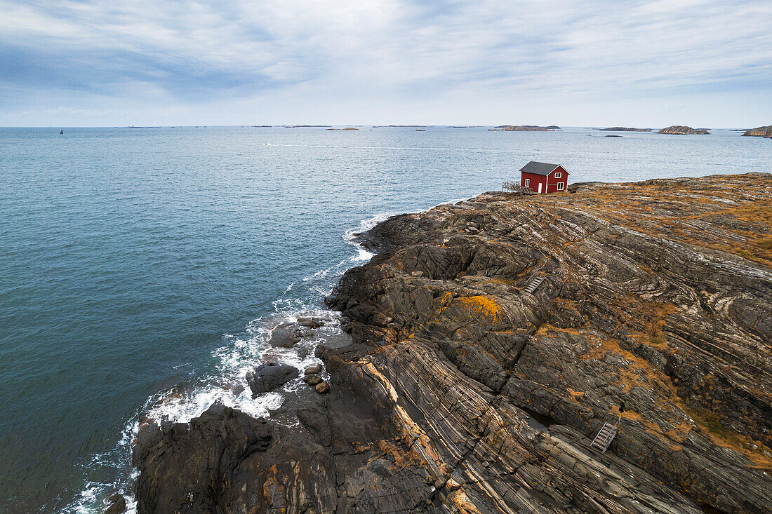 Einsames rotes Haus umgeben von Meer auf einer Klippe einer felsigen Insel, Bohuslan, Vastra Gotaland, Westschweden, Schweden, Skandinavien, Europa