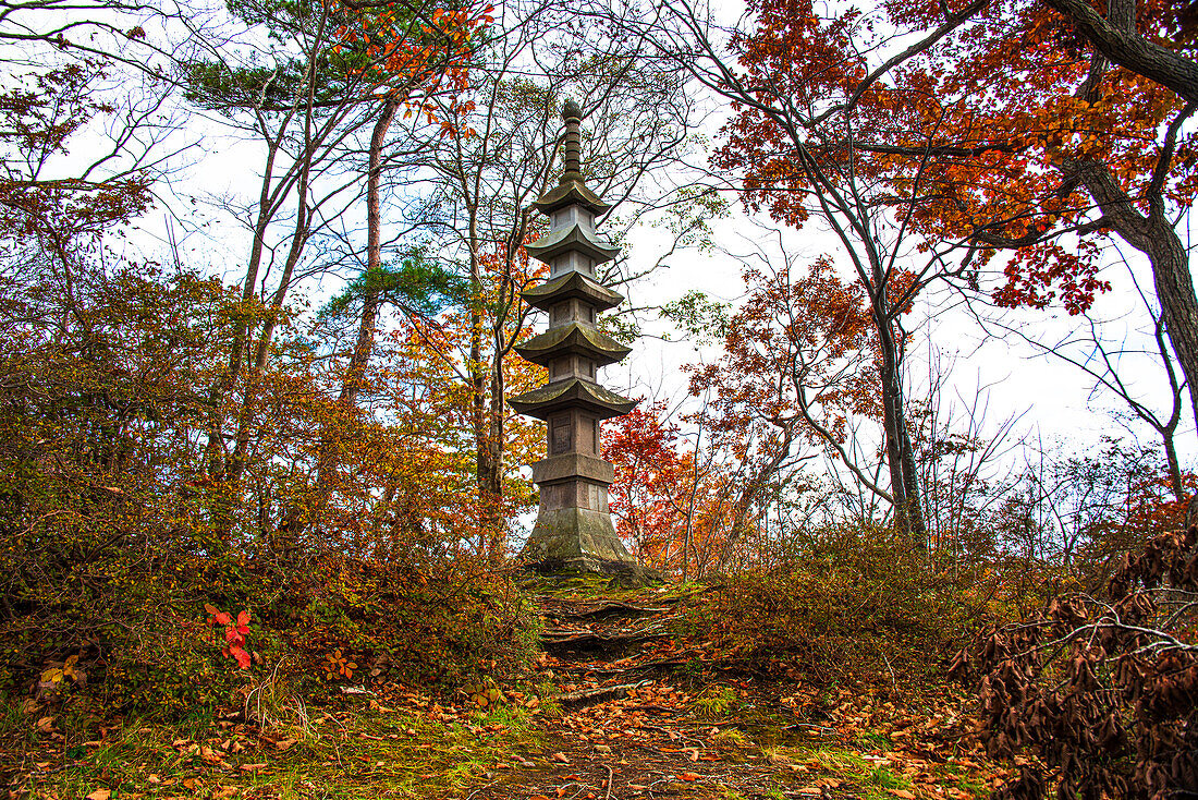 Stone pagoda in a colorful autumnal forest, Japan, Asia\n