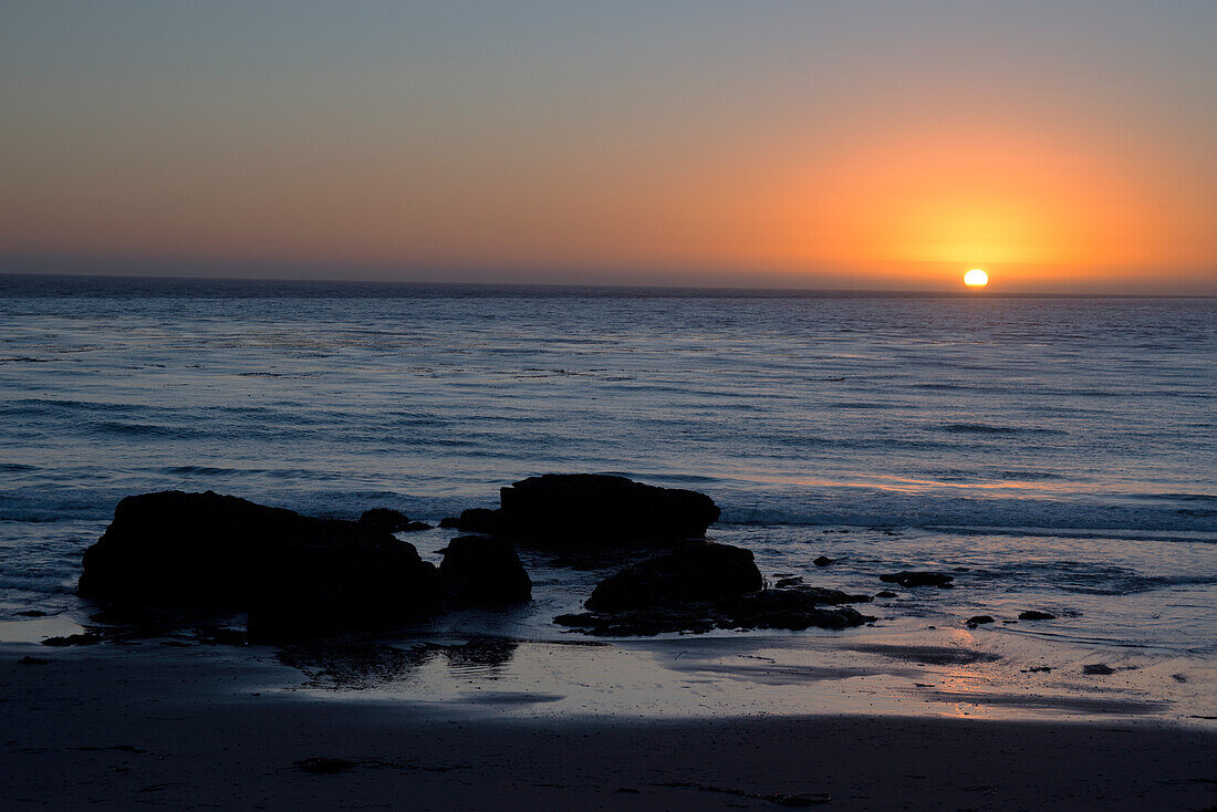 Sonnenuntergang über dem Meer, mit Felsen im Vordergrund, San Simeon, Kalifornien, Vereinigte Staaten von Amerika, Nordamerika