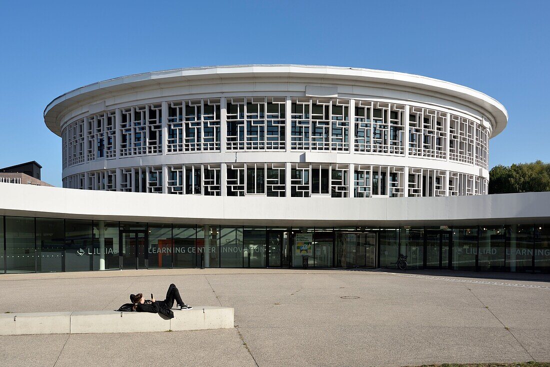 France, Nord, Villeneuve d'Ascq, University of Lille, Cité Scientifique campus, circular building housing the library and called LILLIAD (Learning Center Innovation1), a scientific center of the University of Lille (scientific university library, multimedia, large scientific collection, expanded library and digitized resources), student lying in the sun\n