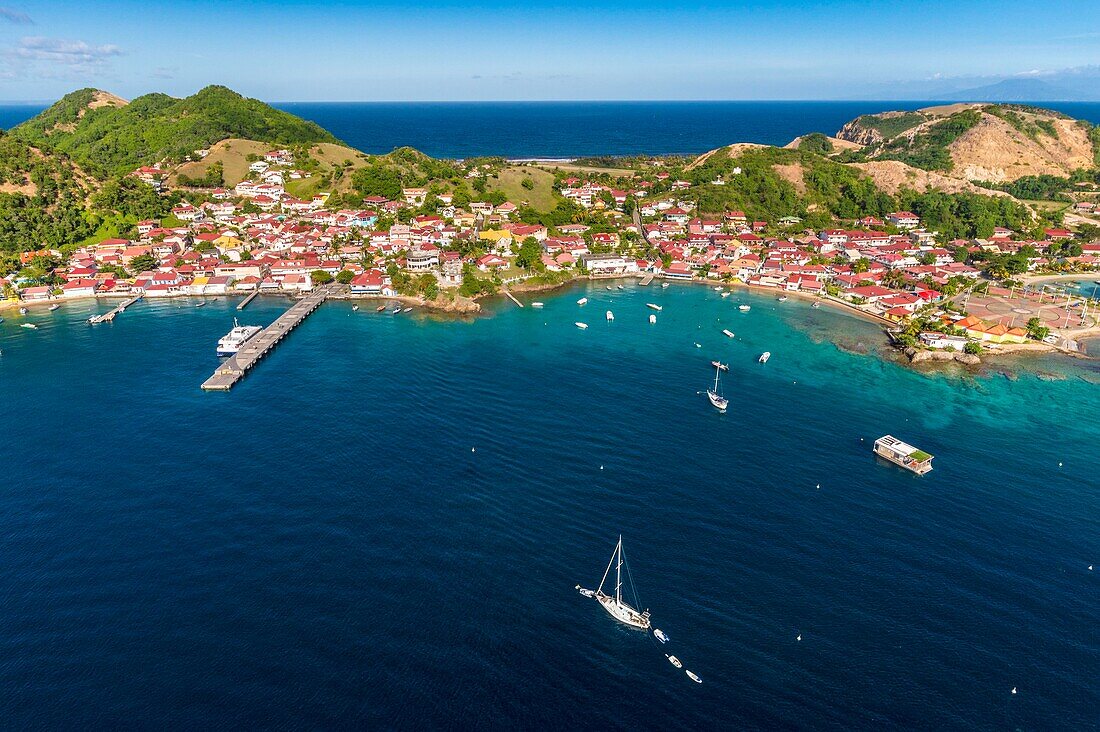 Guadeloupe, Les Saintes, Terre de Haut, the bay of the town of Terre de Haut, listed by UNESCO among the 10 most beautiful bays in the world, Basse Terre background (aerial view)\n