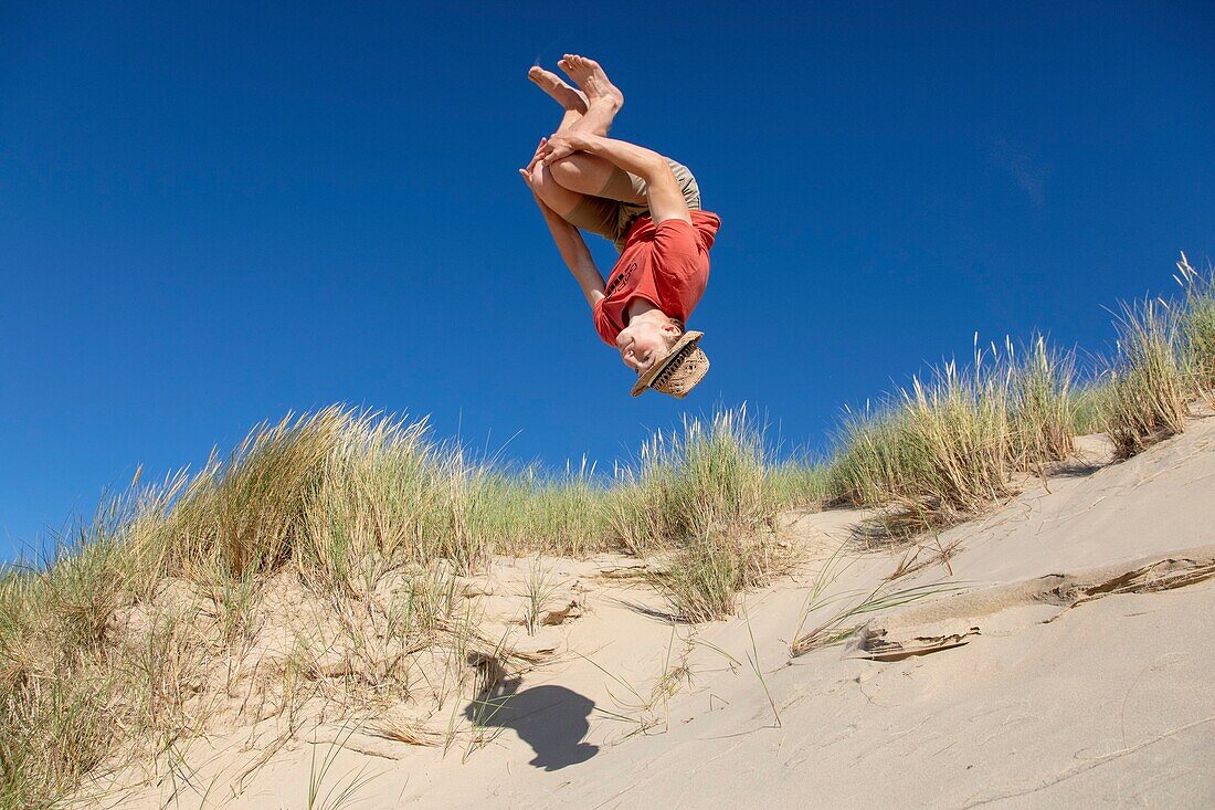 France, Pas de Calais, Wissant, young man doing an acrobatics in the dunes\n