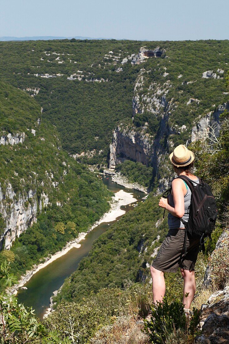 France, Gard, Ardeche Gorges, Aigueze, most beautiful villages of France, Female hiker enjoying the view on the Ardeche river above the village from the Castelviel rock\n
