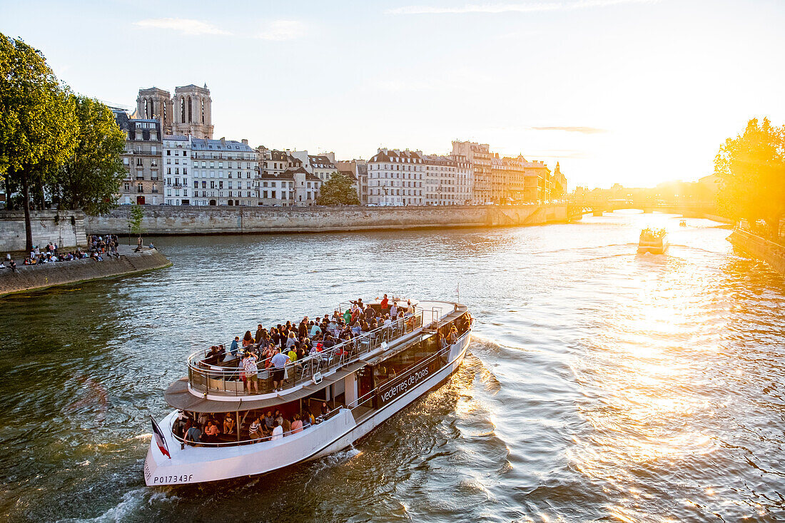 France, Paris, area listed as World Heritage by UNESCO, a fly boat passes in front of Ile de la Cite and Notre Dame Cathedral\n