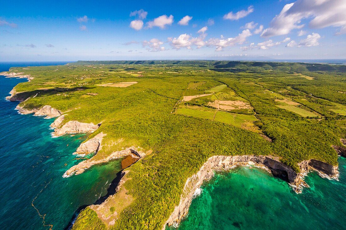 France, Caribbean, Lesser Antilles, Guadeloupe, Guadeloupe, Marie-Galante, Saint-Louis, aerial view of coastal cliffs at Madame Cove, Dominica island in the background\n