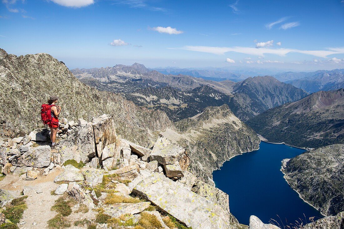 France, Hautes Pyrenees, Pyrenees National Park, young hiker at the top of the Peak of the Turon de Néouvielle (3035m), view below on Lake Cap de Long (2161m)\n