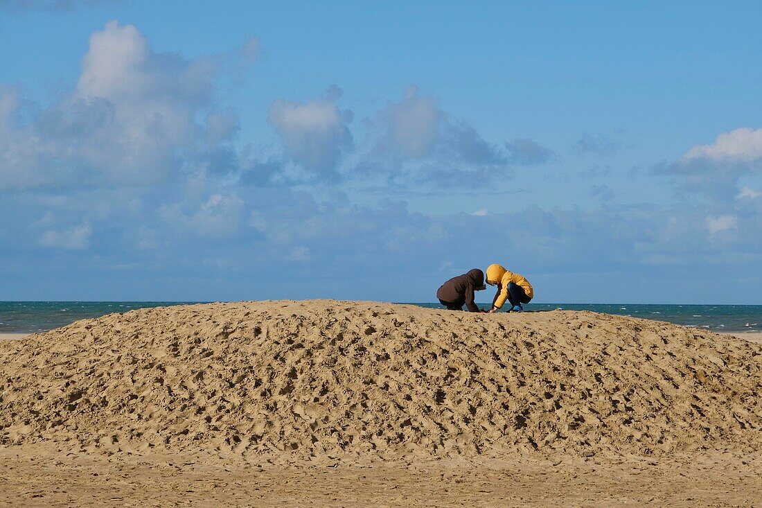 France, Calvados, Pays d'Auge, Deauville, the beach, two boys play in the sand\n