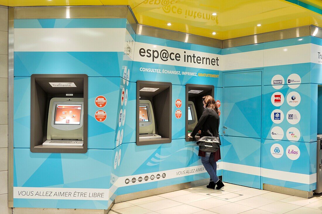 Frankreich, Nord, Lille, Servicebereich im Bahnhof Lille Flandres, junge Frau von hinten beim Kauf einer Fahrkarte am Geldautomaten