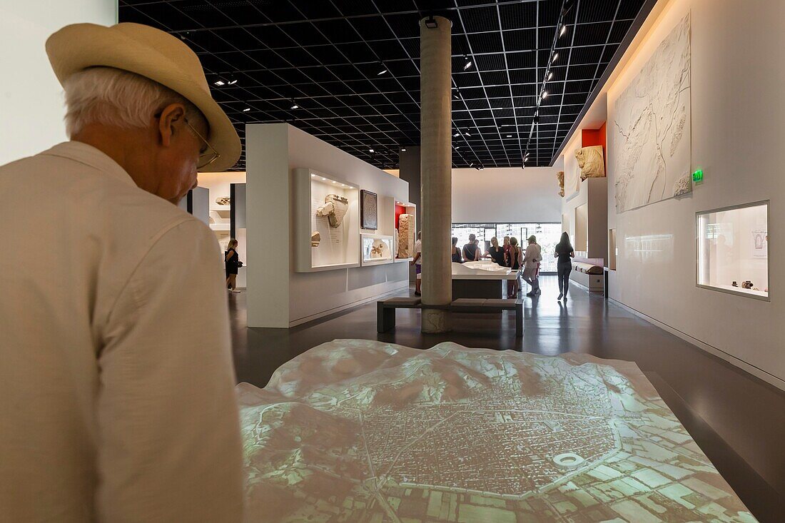 France, Gard, Nimes, Musee de la Romanite by architect Elizabeth de Portzamparc, visitor in front of a scale model animated by video mapping, presenting the urban evolution of Nîmes in Roman times\n