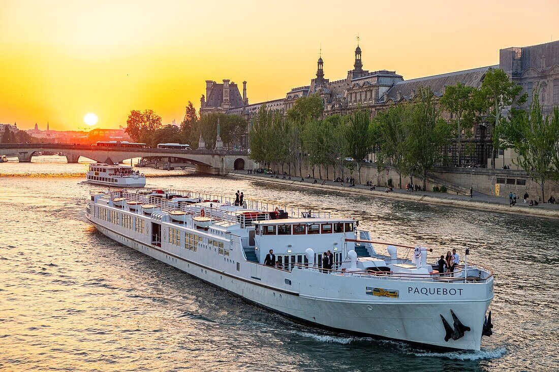 Frankreich, Paris, von der UNESCO zum Weltkulturerbe erklärtes Gebiet, ein festliches Kreuzfahrtschiff fährt bei Sonnenuntergang am Louvre vorbei