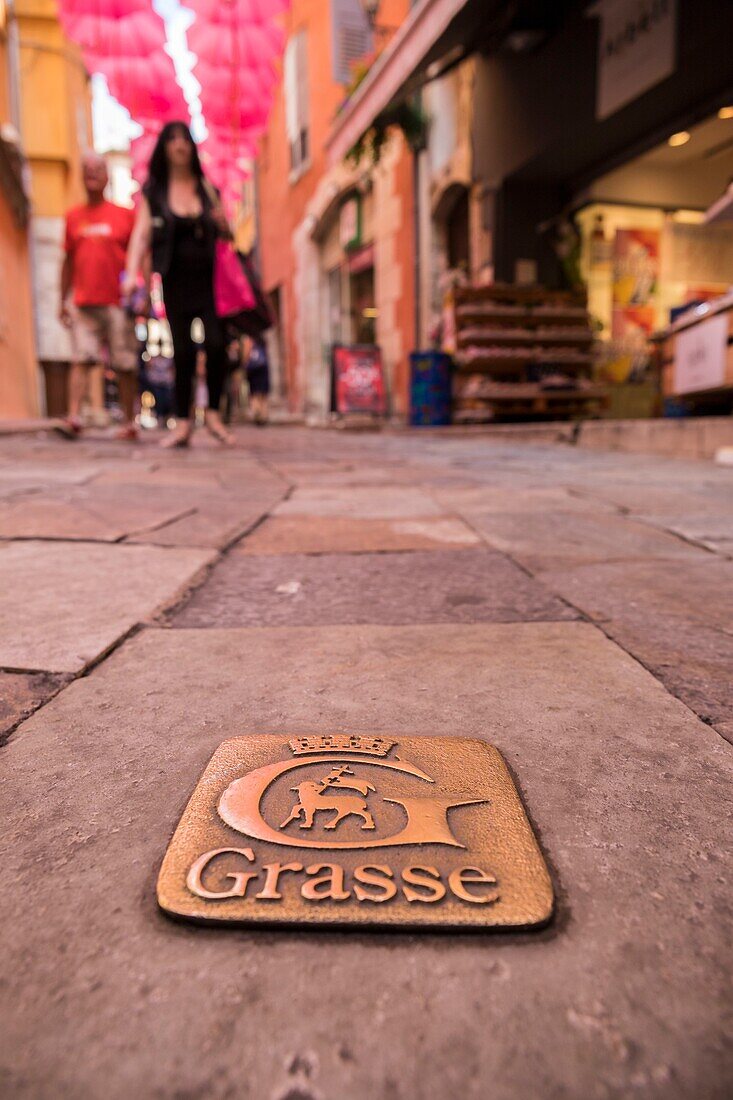 France, Alpes-Maritimes, Grasse, crest of the city of Grasse on the paved ground of the street of the Oratory\n