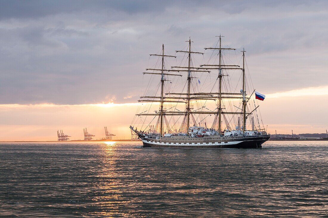 Frankreich, Calvados, Honfleur, Armada 2019, Grande Parade, Kruzenshtern, Viermastschoner, der in der untergehenden Sonne die Seine-Mündung verlässt, mit dem Hafen von Le Havre im Hintergrund