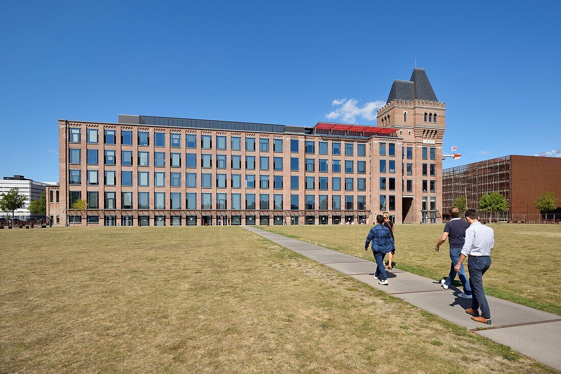 Frankreich, Nord, Lille, Bezirk Bois Blancs, EuraTechnologies business park pole of excellence, der dem TIC der Metropole Lille gewidmet ist, in der Blan Lafont, einer alten Spinnerei aus dem Jahr 1900, drei Männer und eine Frau von hinten gesehen, die auf einem Weg zum Hauptgebäude gehen