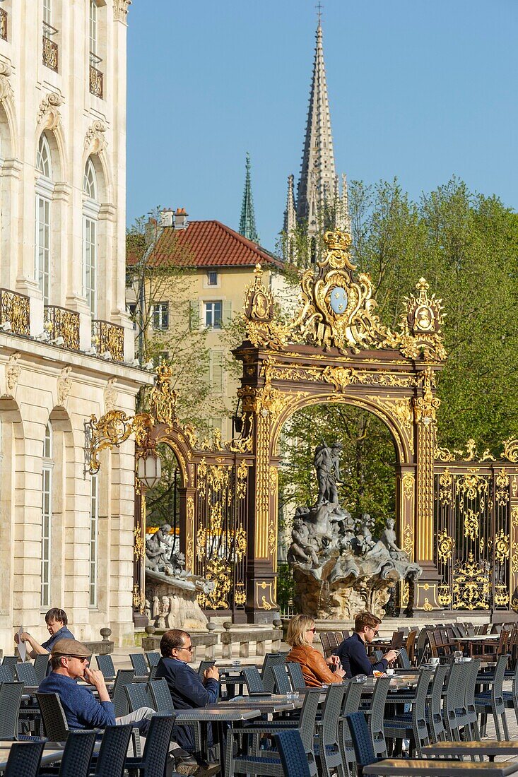 France, Meurthe et Moselle, Nancy, Stanislas square (former royal square) built by Stanislas Leszczynski, king of Poland and last duke of Lorraine in the 18th century, listed as World Heritage by UNESCO, detail of the facade of the Musee des Beaux Arts (Fine arts museum), railings and street lamps by Jean Lamour, Neptune fountain and Saint Epvre basilica bellfry in the background\n