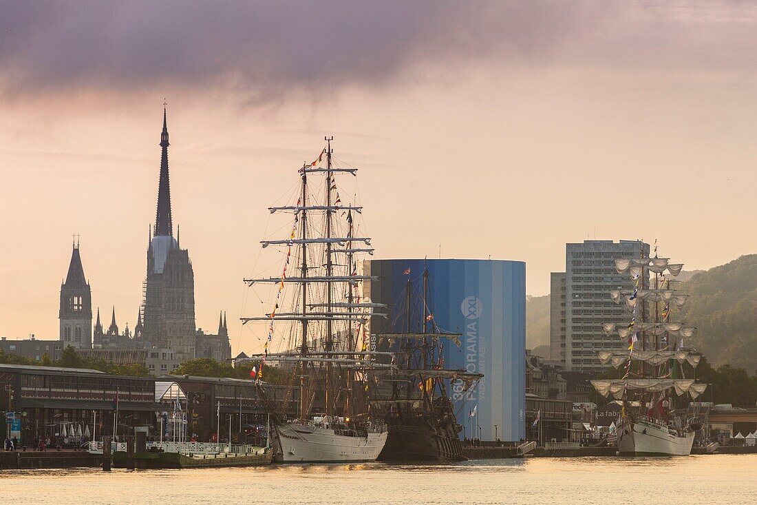 France, Seine Maritime, Rouen, Armada 2019, sunrise over tall ships moored in the docks of the Seine River, with Rouen Cathedral and Panorama XXL in the backgroung\n