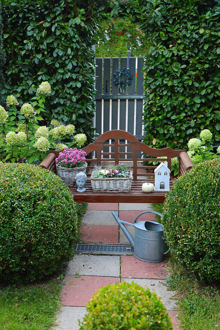 Garden bench with asters, bust and little house, decorated for autumn