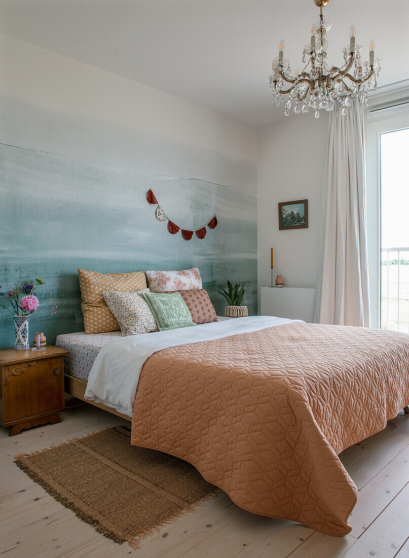 Bedroom with orange quilt, mural and chandelier