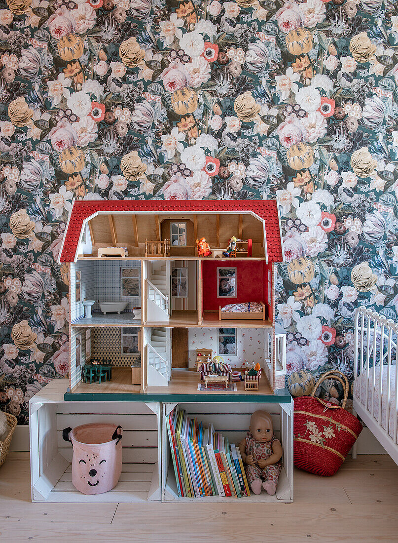 Puppenhaus auf Holzkisten vor Blumentapete im Kinderzimmer