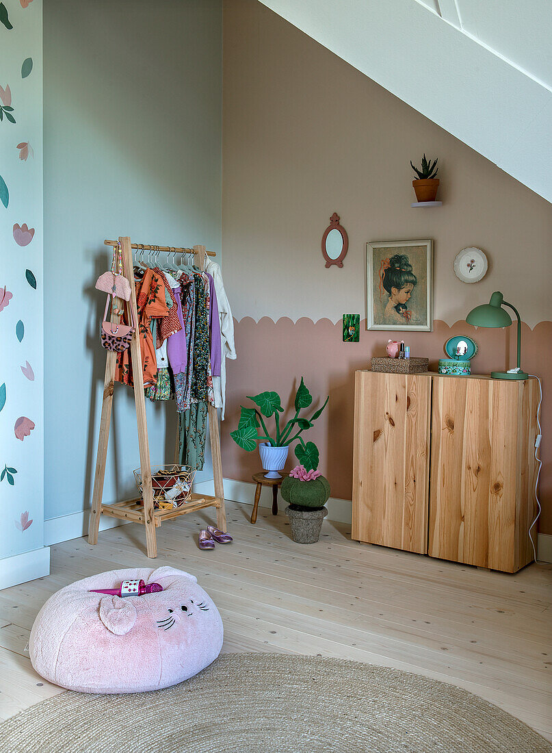 Kinderzimmer mit Holzschrank, Kleiderständer und Sitzkissen