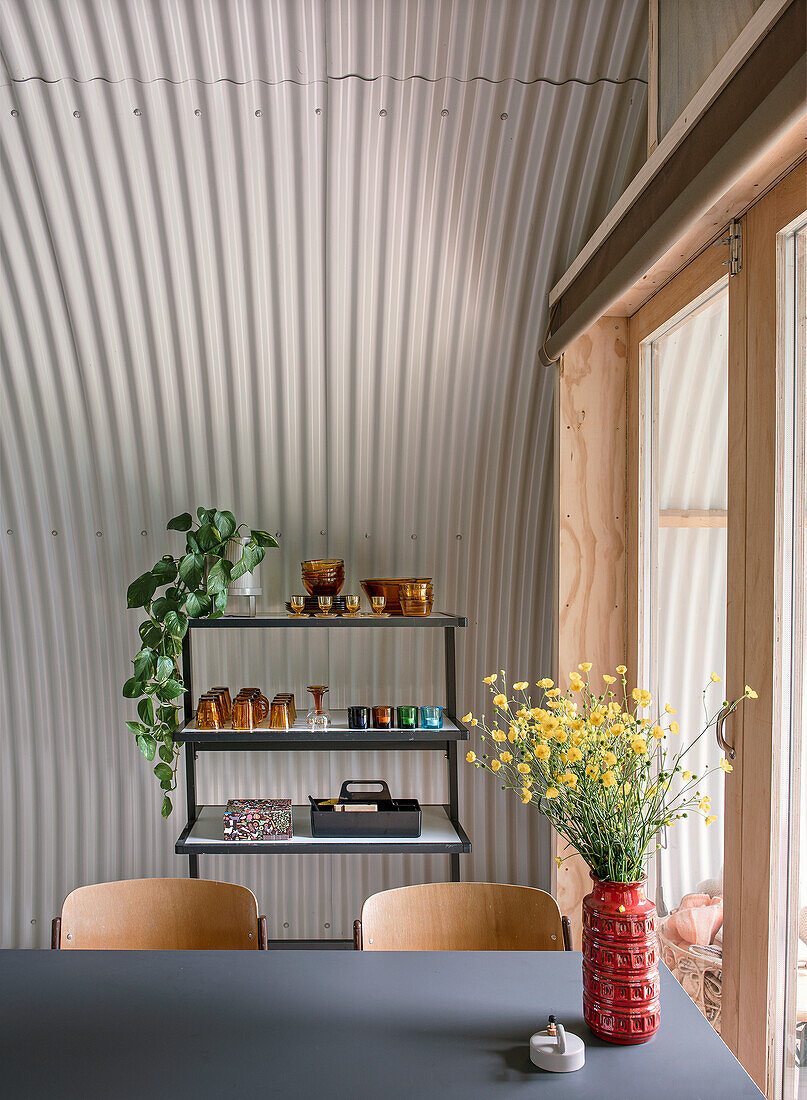 Arched room with metal wall, shelf and yellow flowers in a red vase