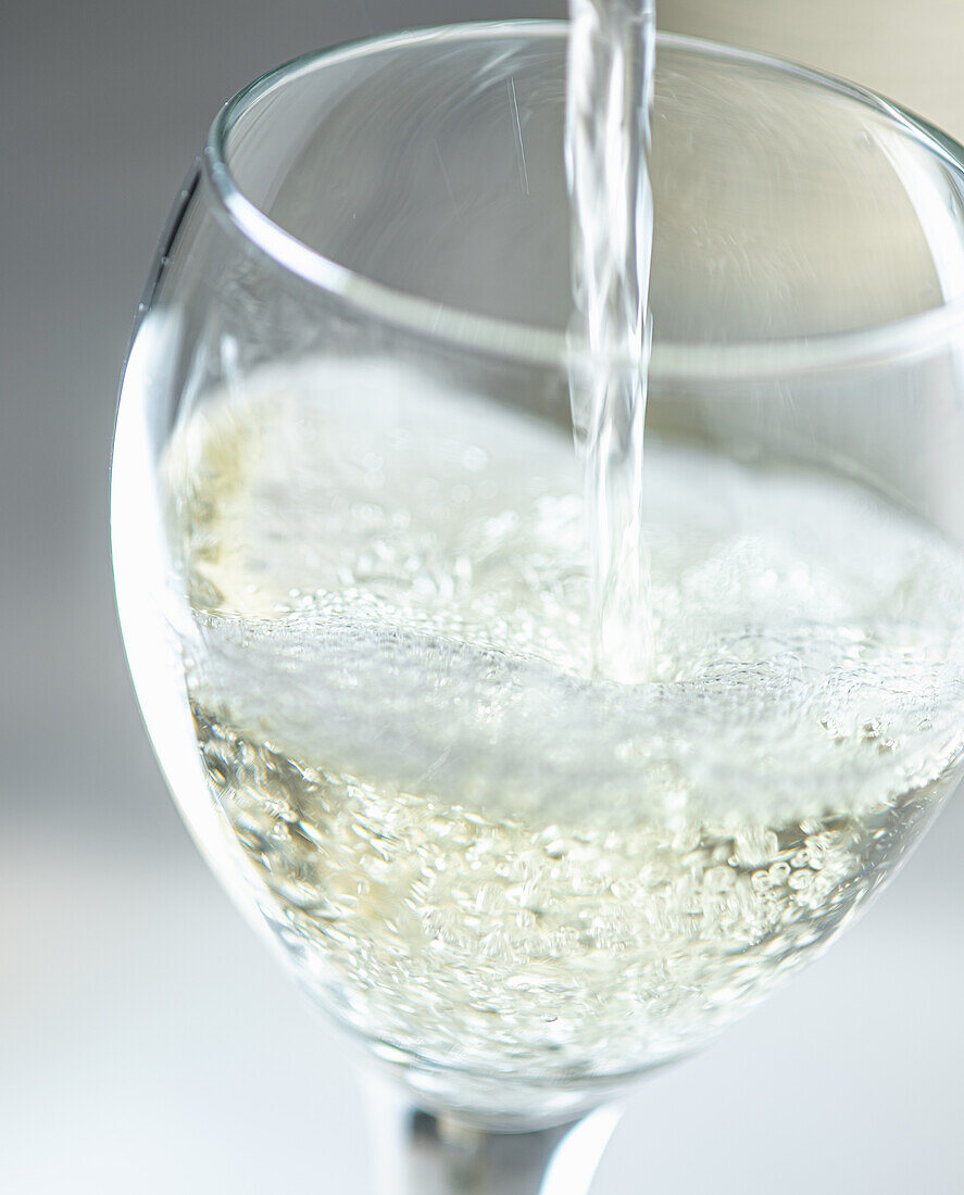 Weißwein in ein Glas giessen