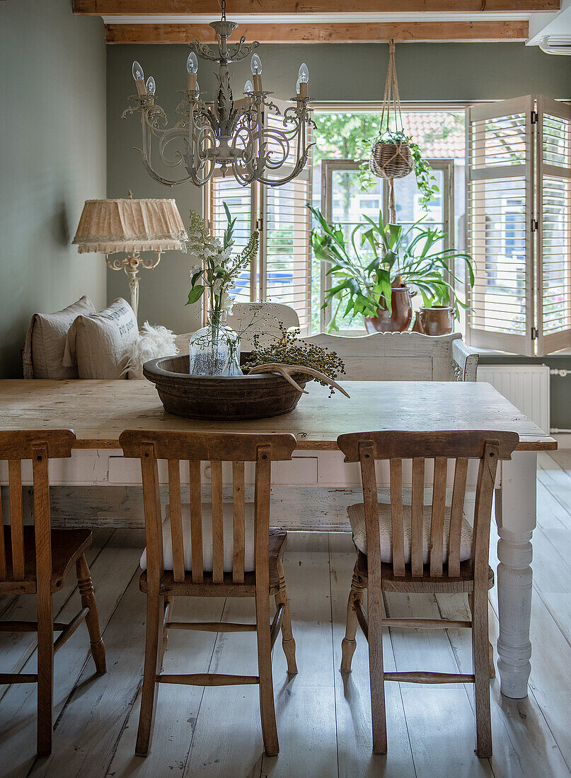 Dining room with rustic wooden table, vintage chairs and chandelier