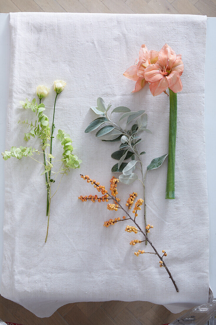 Apricotfarbene Amaryllis, Salbeiblätter, gelbe Ilexbeere und weiße Lisianthus