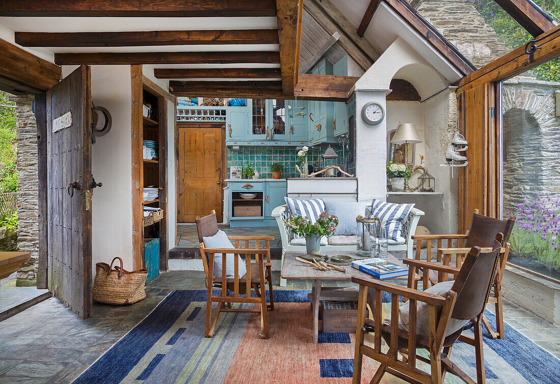 Conservatory with wooden beamed ceiling, seating area and open-plan kitchen in country house style