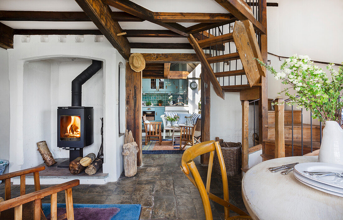 Rustikales Wohnzimmer mit Holzofen, sichtbaren Balken und Steinboden