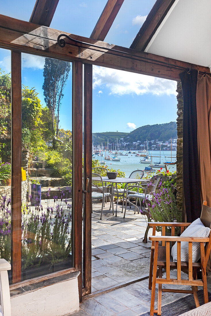 Glas-Schiebetür zu Terrasse mit Blick auf Hafen und Hügel im Sommer