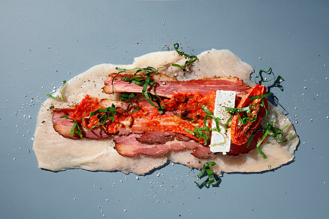 Preparing corn-fed chicken with a cream of sun-dried tomatoes, pastrami and feta