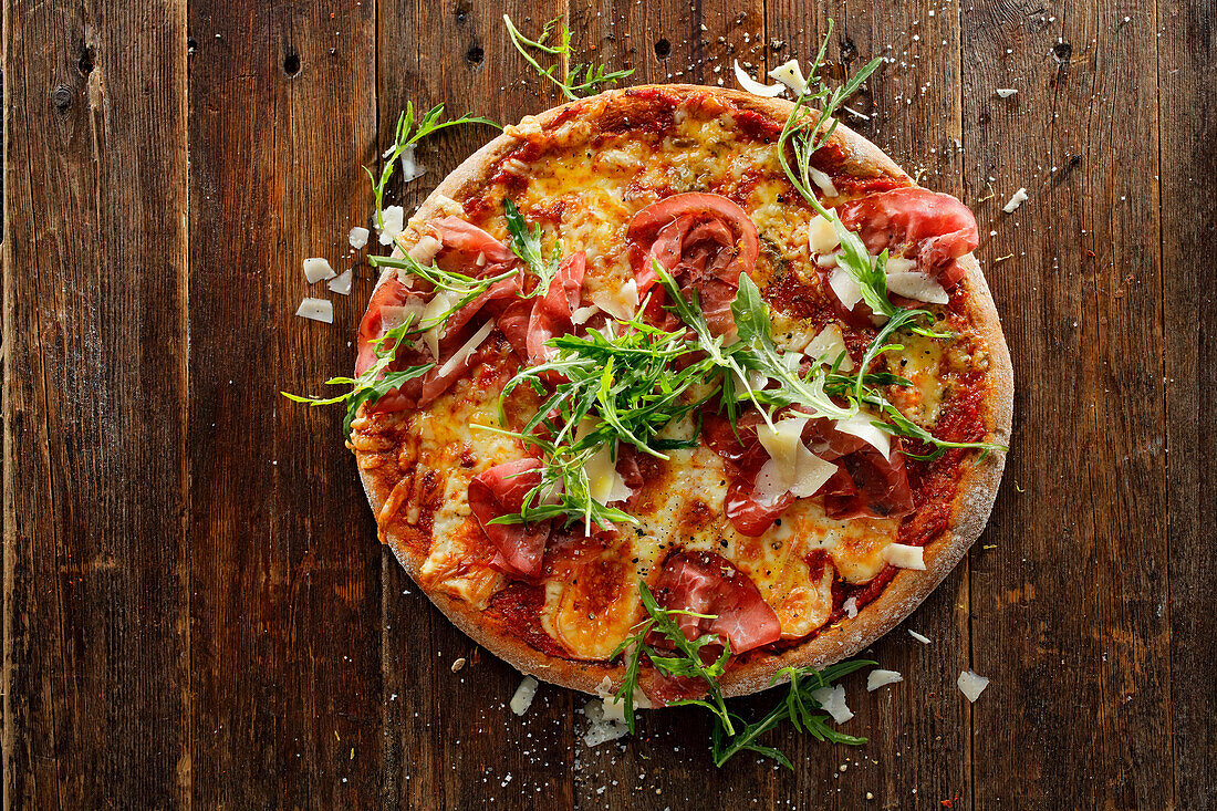 Wholemeal pizza with four types of cheese, sun-dried tomatoes, bresaola and rocket salad