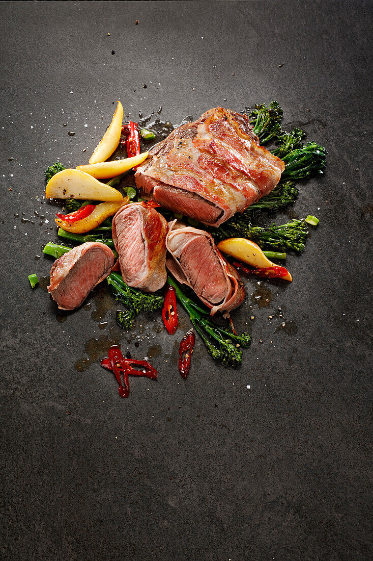 Beef steak wrapped in bacon with broccolini and pears