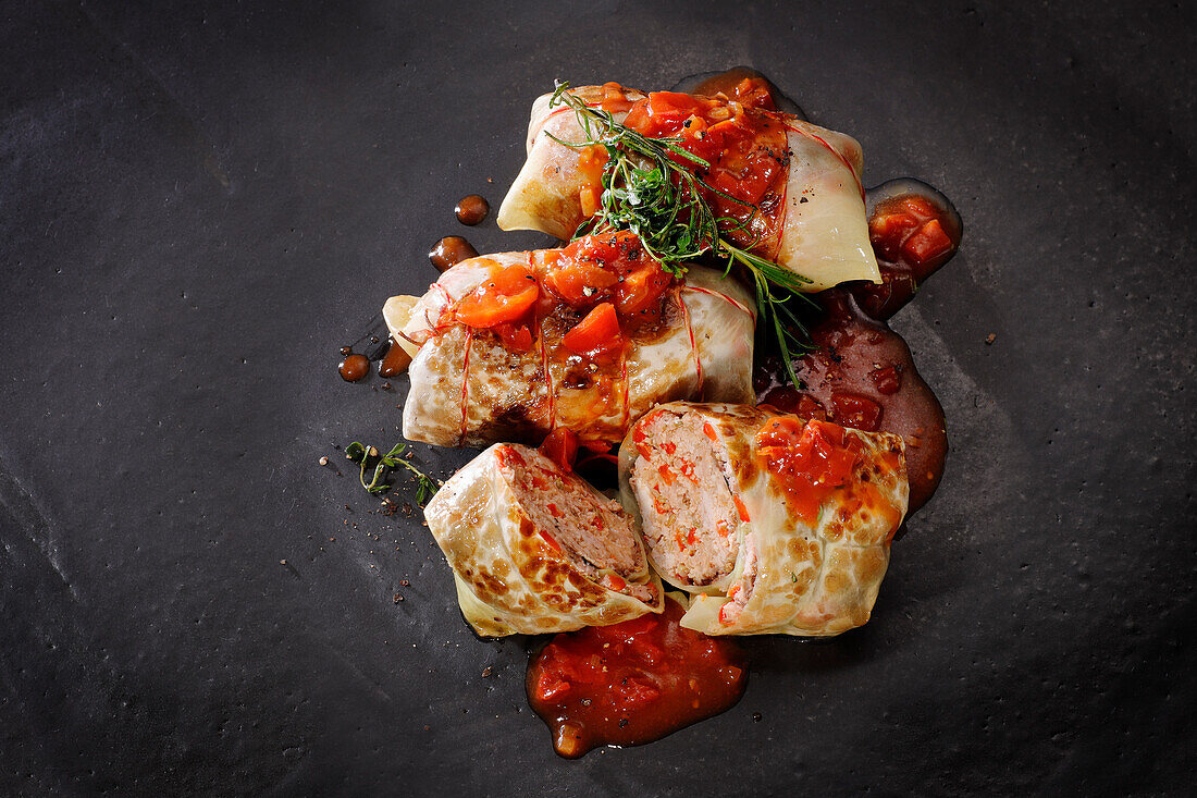 White cabbage roulades with tapenade, sausage and grilled peppers in tomato sauce