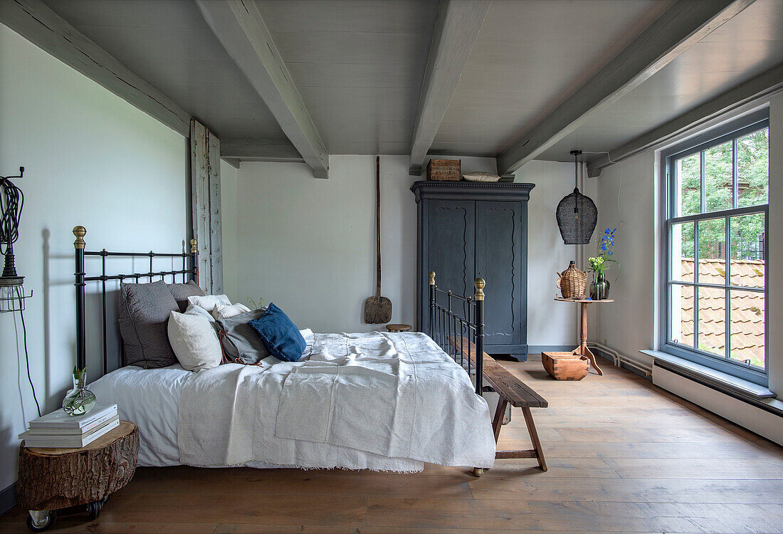 Bedroom with metal bedframe, antique wardrobe and light-colored wooden floor