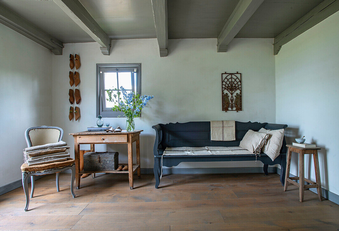 Sitting area with blue-grey bench, antique wooden furniture and wooden beamed ceiling