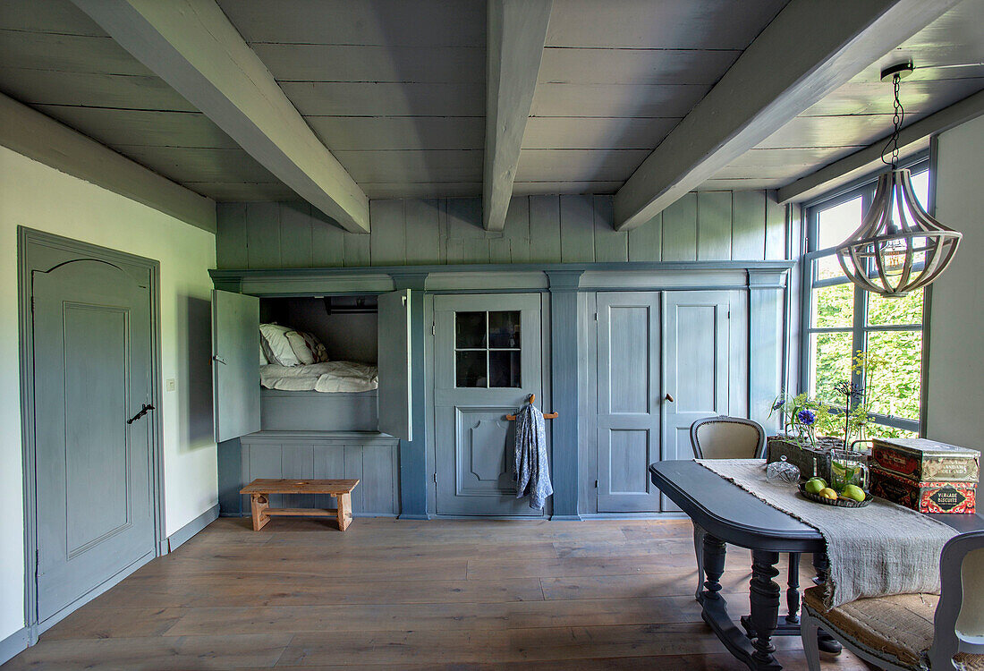 Bedroom in blue and grey tones with alcove bed and wooden beamed ceiling