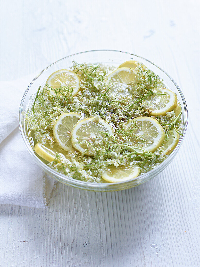 Making elderflower syrup: Elderflowers with lemon slices and water