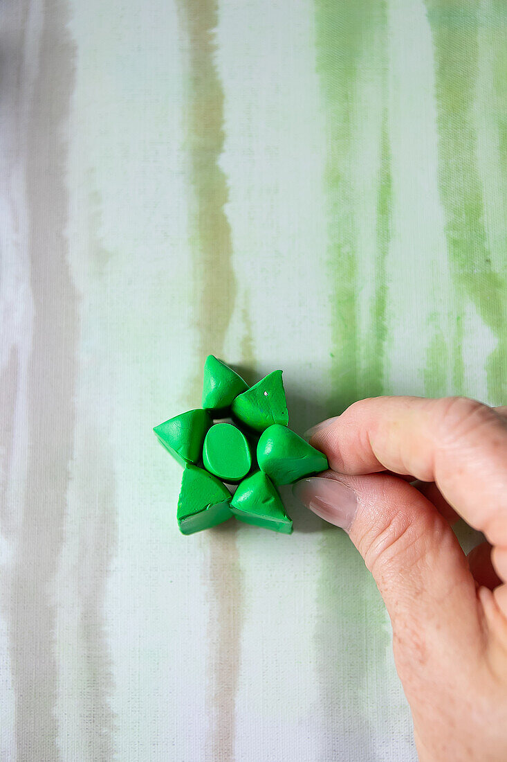 DIY decoration made from green modelling clay in the shape of a star on a striped background