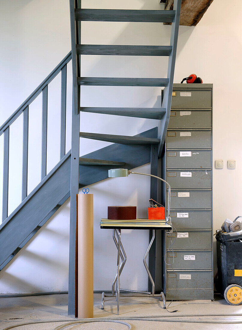 Workshop corner with metal staircase, filing cabinet and table